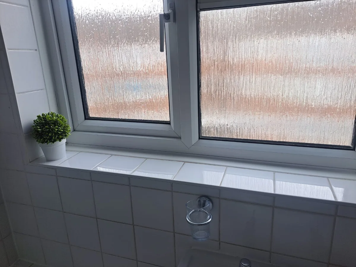 Clean bathroom window and tiled sill after inside window cleaning